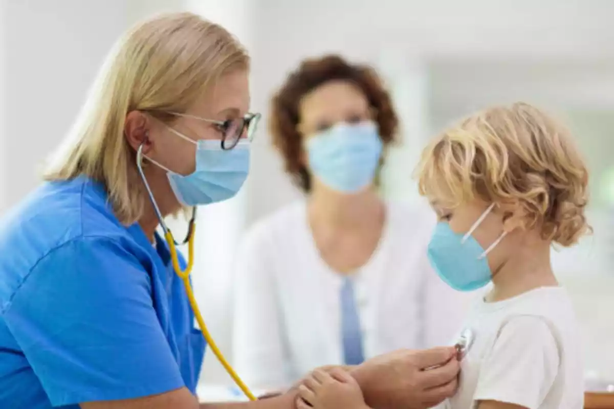 Pediatra con mascarilla atendiendo a un niño con mascarilla