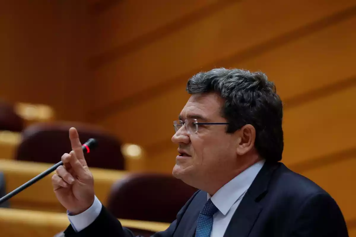 Primer plano de perfil del ministro José Luis Escrivá con el dedo índice levantado