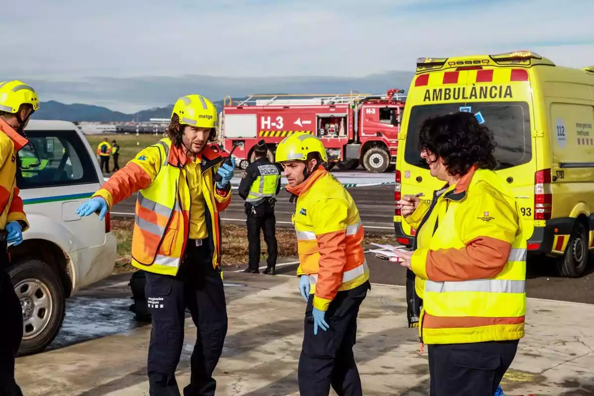 Sanitarios organizando un servicio con una ambulancia y un camión de bomberos de fondo
