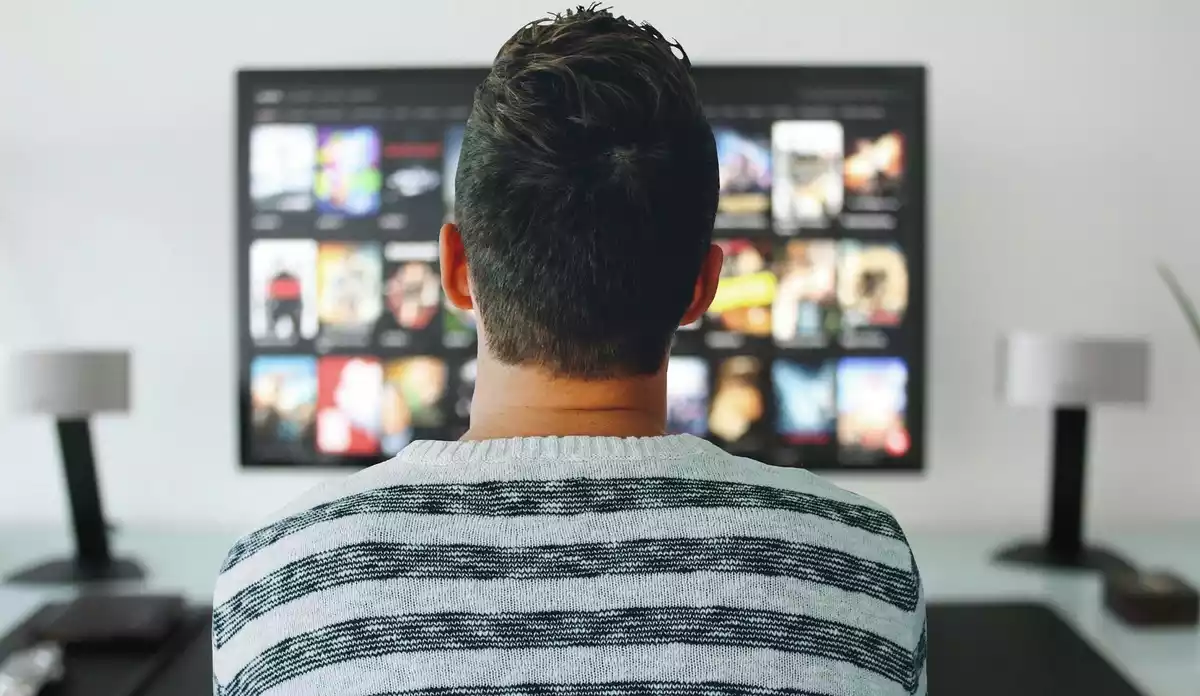 Un hombre mirando una smart TV con muchas películas para escoger