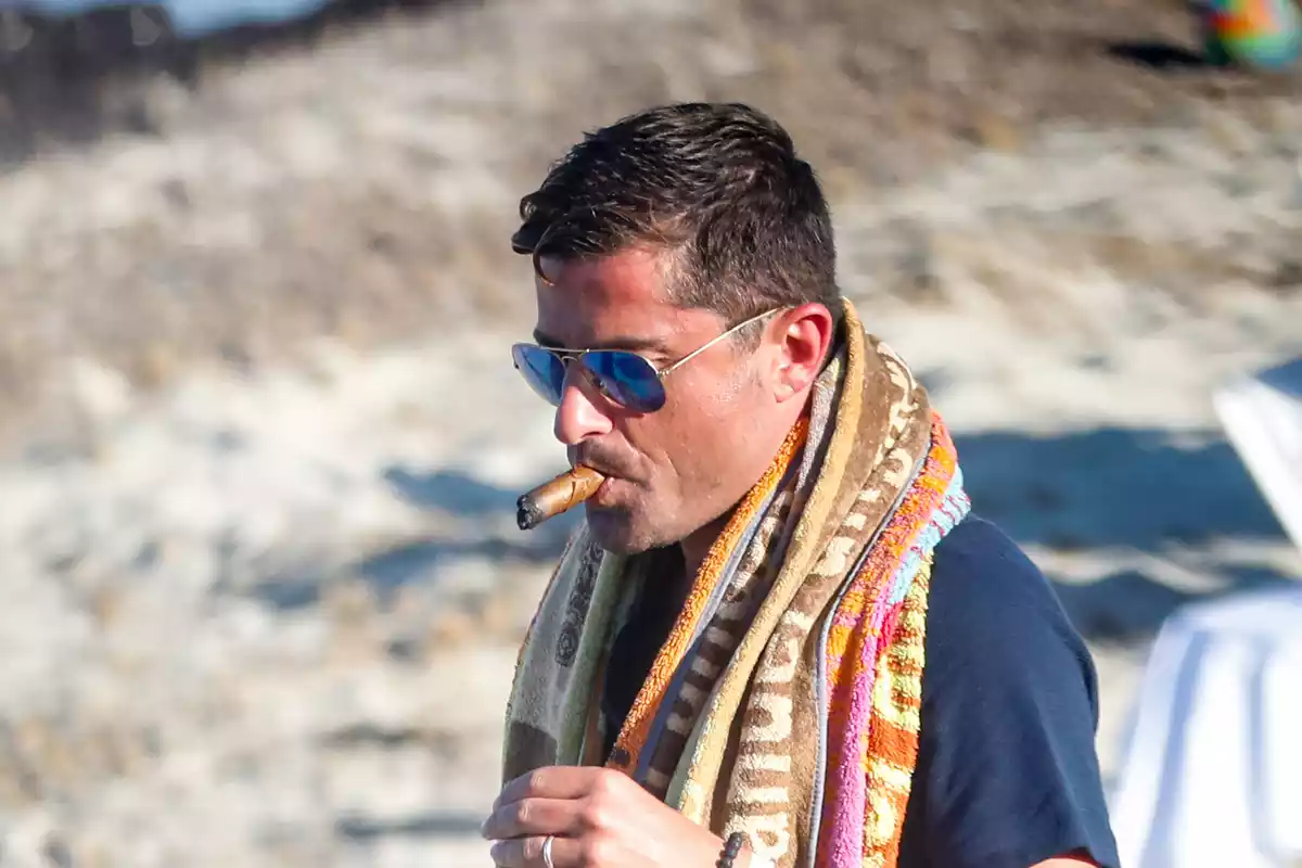 Alfonso Merlos en la playa con gafas de sol y fumando un puro