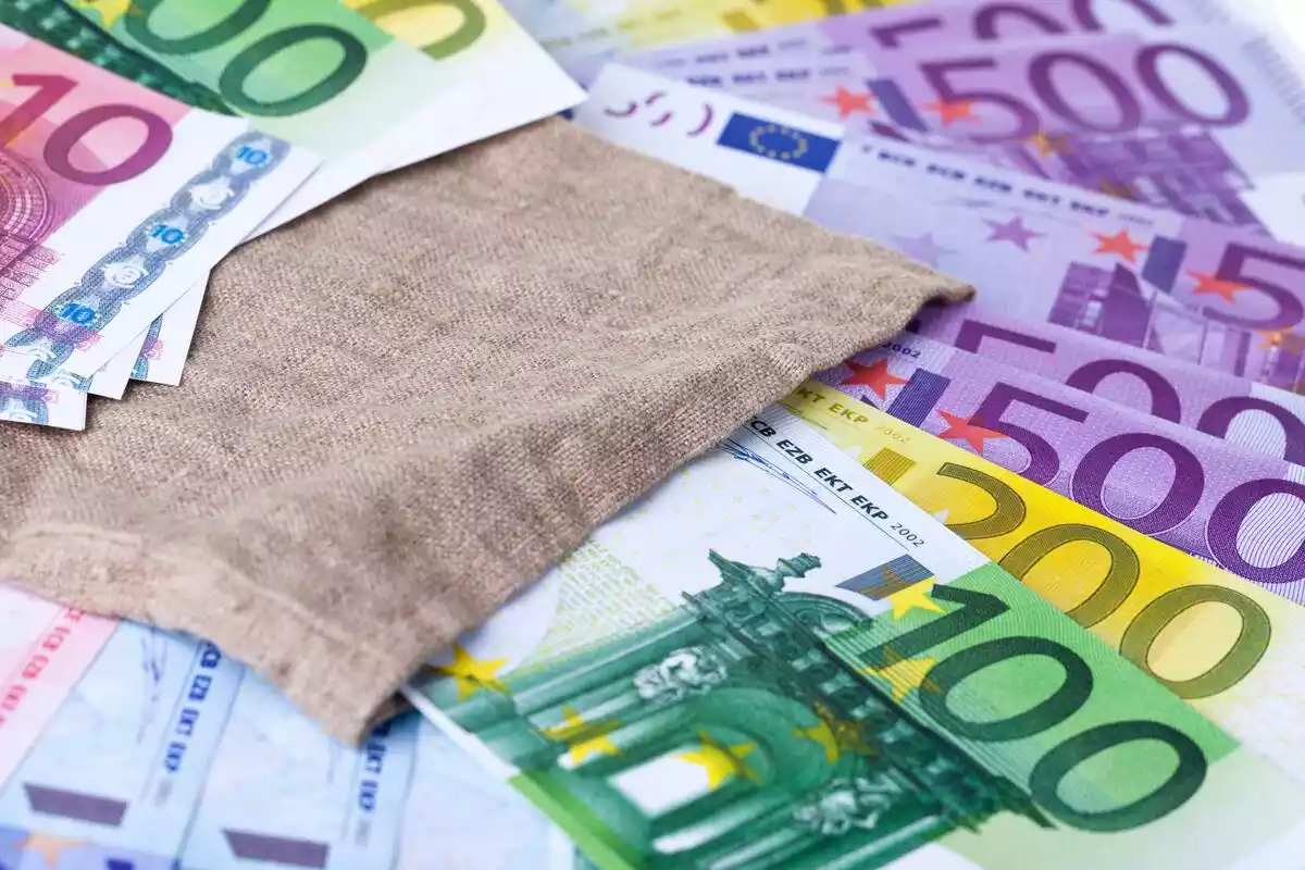 Billetes de euros sobre una mesa ordenados y con un trapo color tierra cubriendo una parte