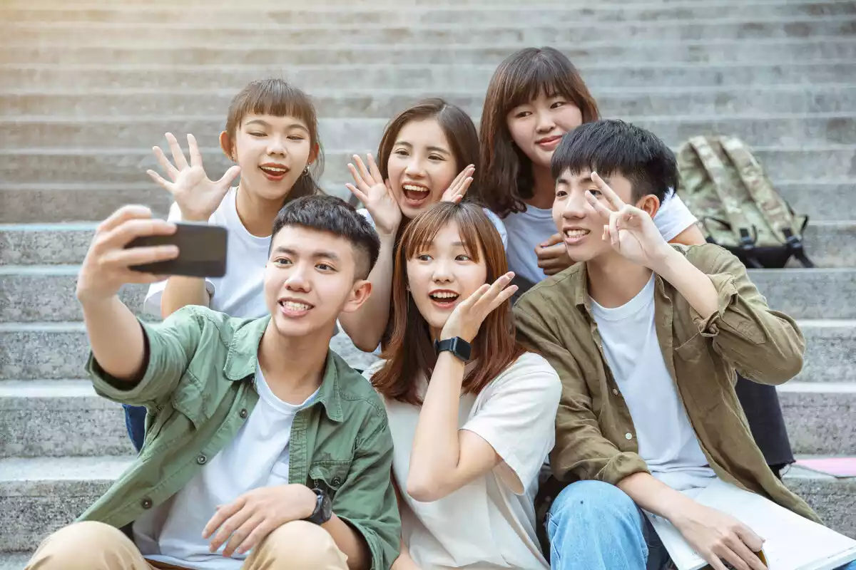 Grupo de jóvenes sentados en la calle posando para una selfie