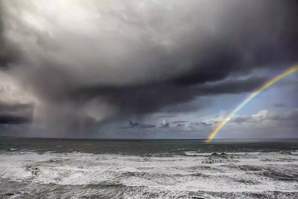 Imagen de un arco iris en una playa del Cantábrico