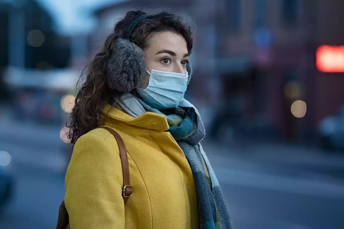 Mujer en invierno usando una mascarilla en la calle en la ciudad