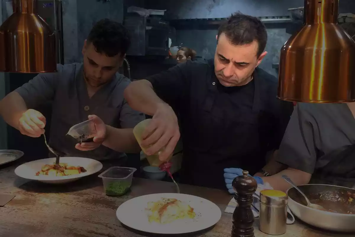 Nacho Basurto preparando un plato acompañado de un ayudante de cocina