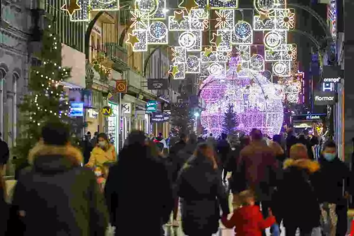 Personas andando por las calles de Vigo decoradas de Navidad
