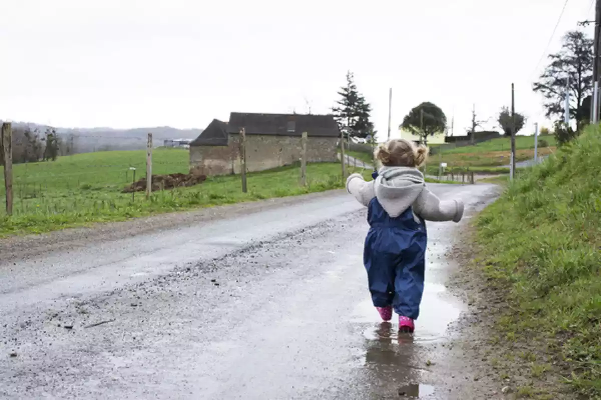 Una niña andando por un camino encharcado