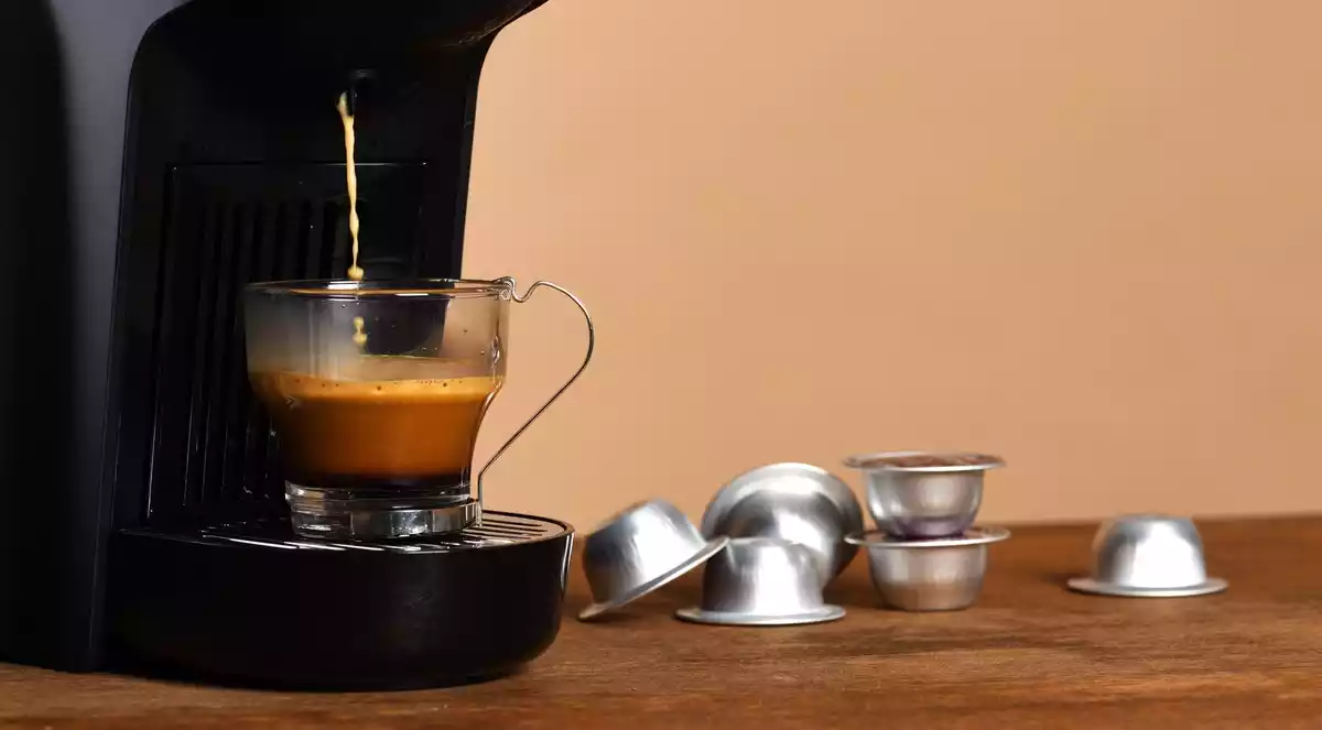 Imagen de archivo de una cafetera, una taza y cápsulas de café