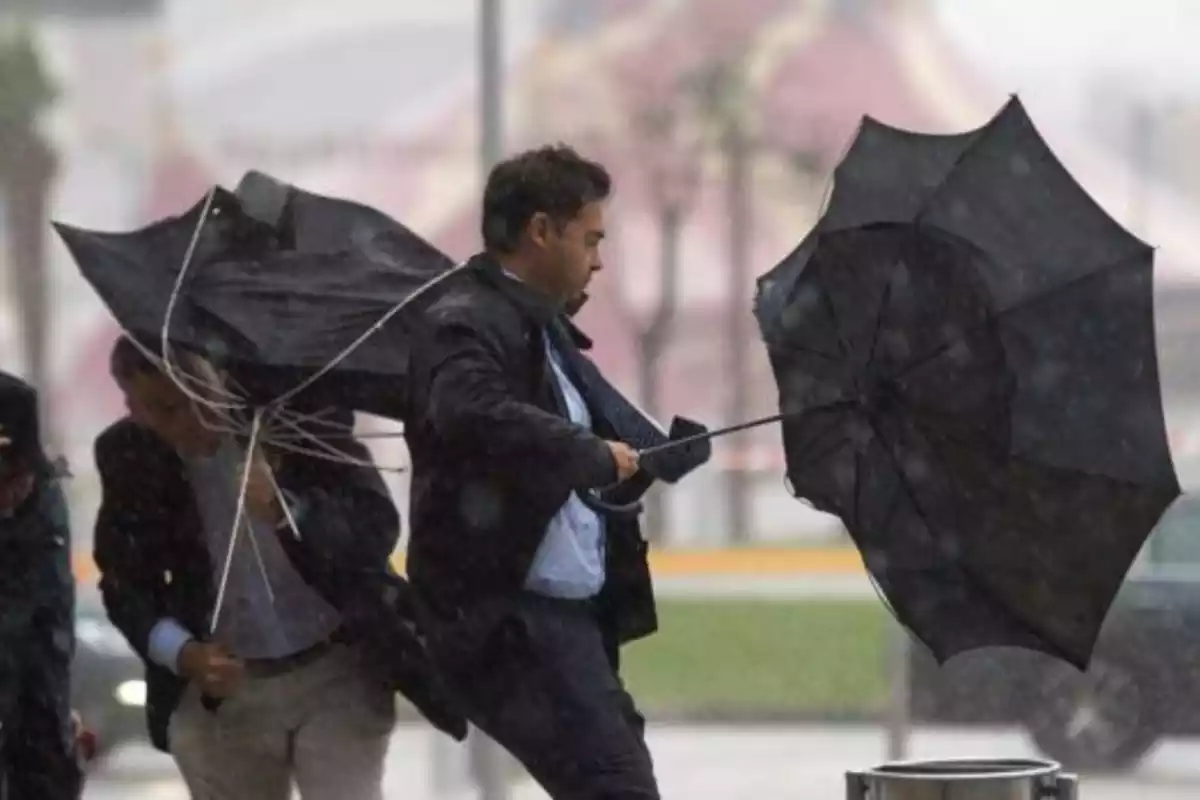 Imagen de un hombre aguantando su paraguas en pleno temporal