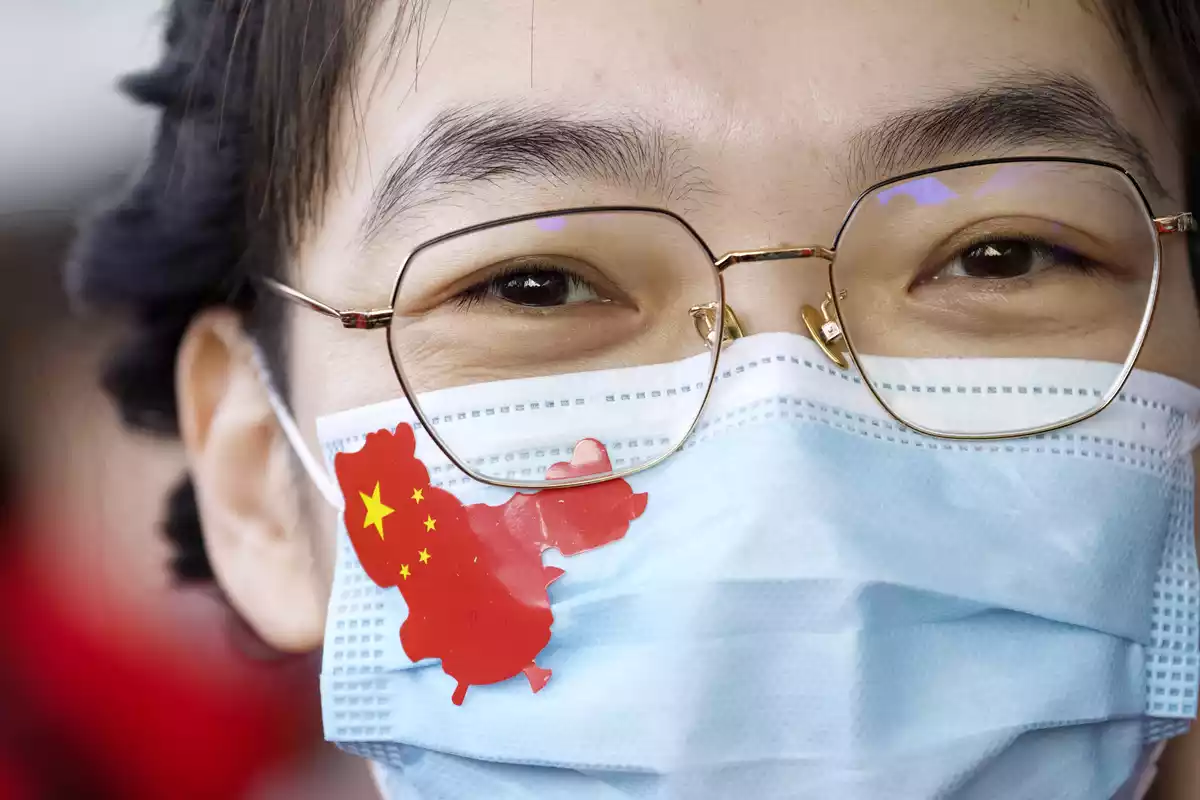 Primer plano de un ciudadano chino con una mascarilla con el mapa y la bandera de china