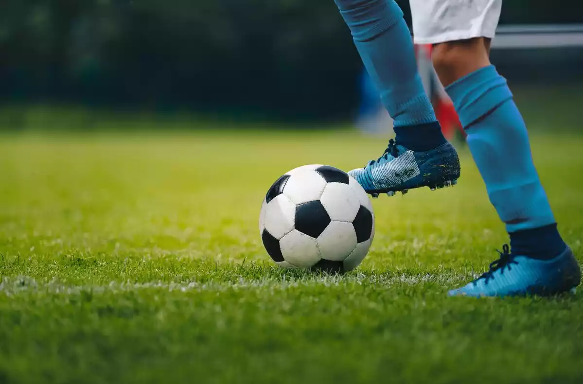 Un futbolista golpea un balón de fútbol con sus pies