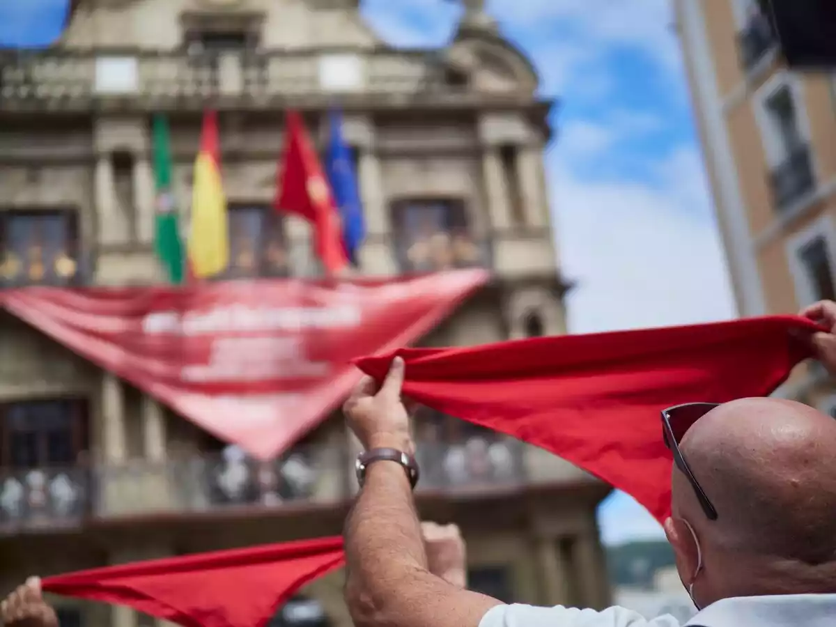 Un hombre alza un pañuelo rojo típico de los Sanfermines de Pamplona