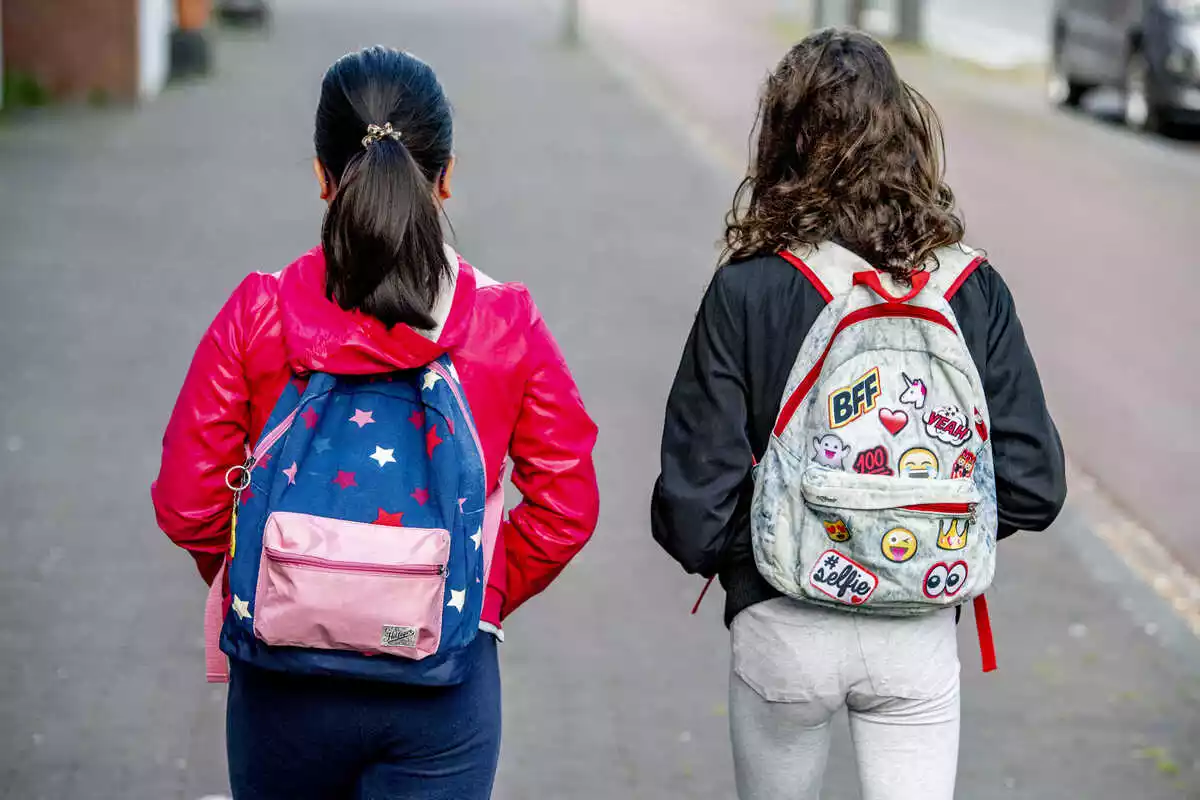 Dos niñas con mochila y de espalda dirigiéndose al colegio