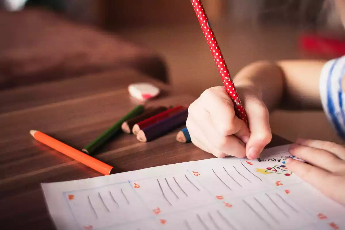La mano de una niña coloreando un libro