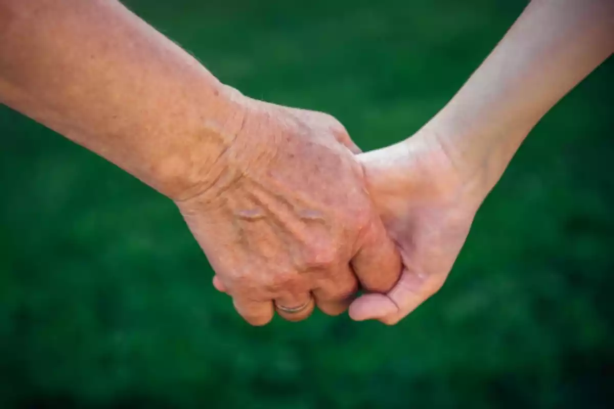 Mano de una anciana sosteniendo la mano de una niña
