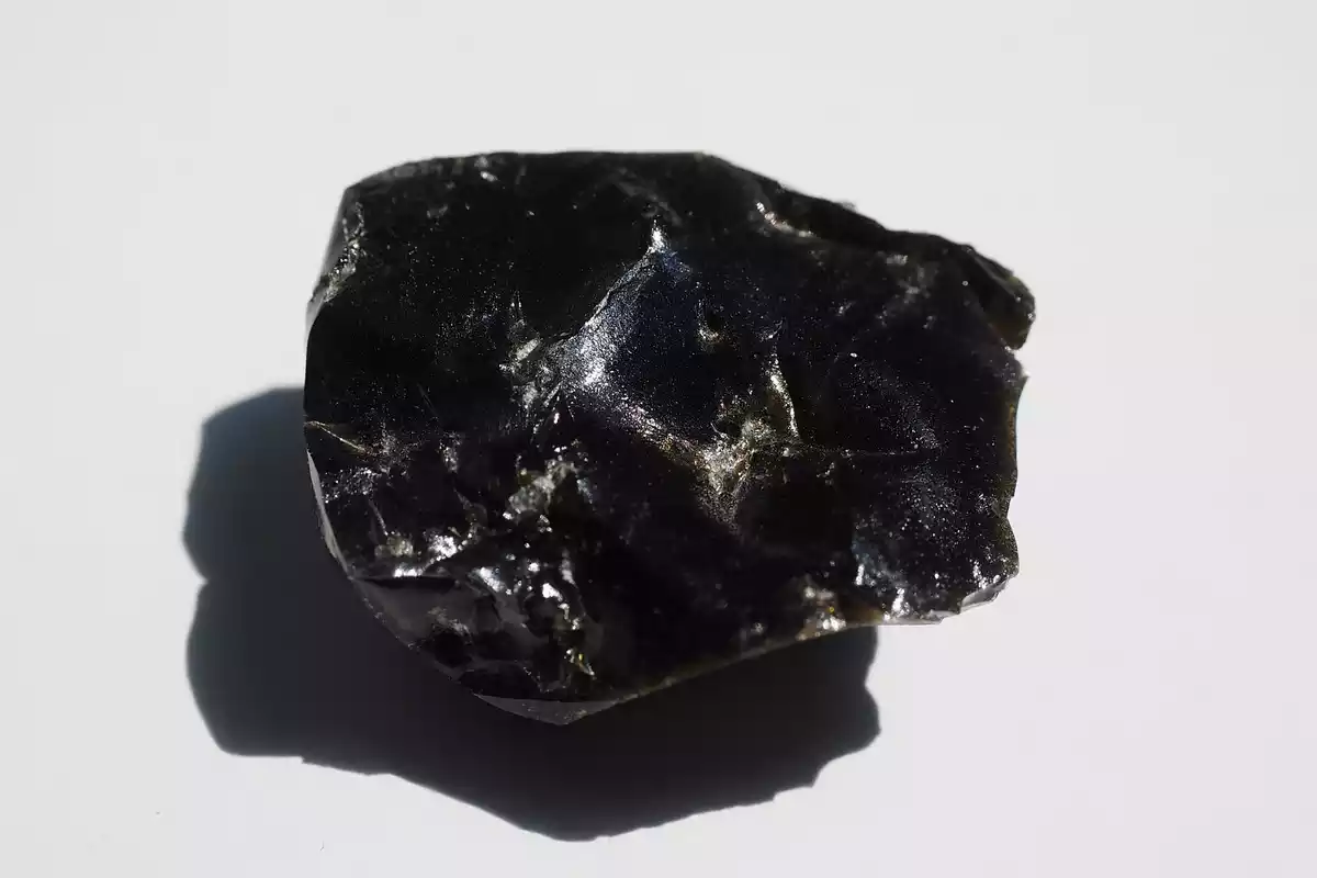 Un trozo de mineral de Obsidiana sobre un fondo blanco