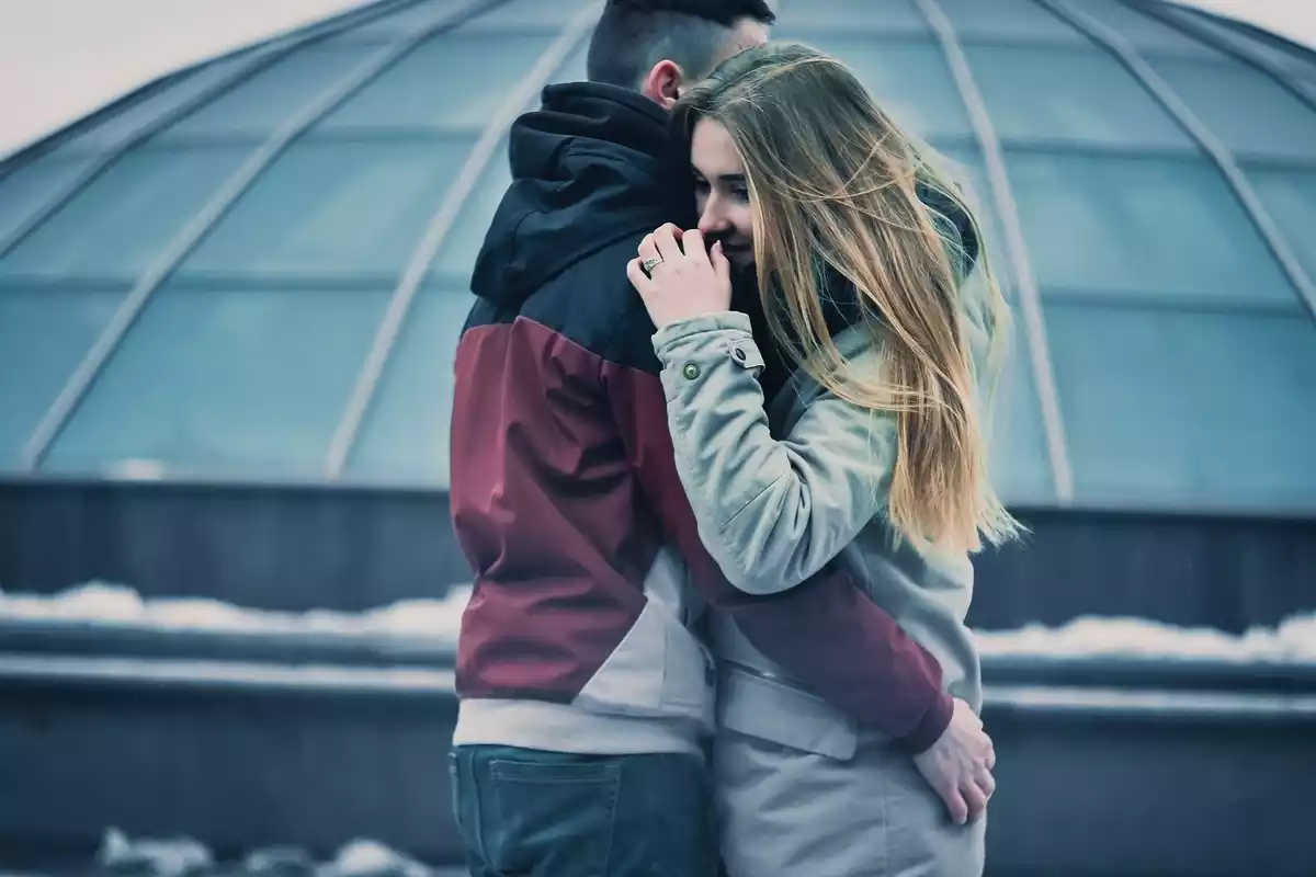 Una pareja enamorada y abrazada delante de un edificio