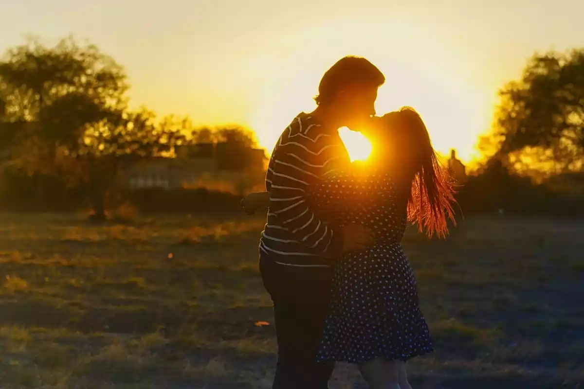 Una pareja feliz besándose delante de una puesta de sol