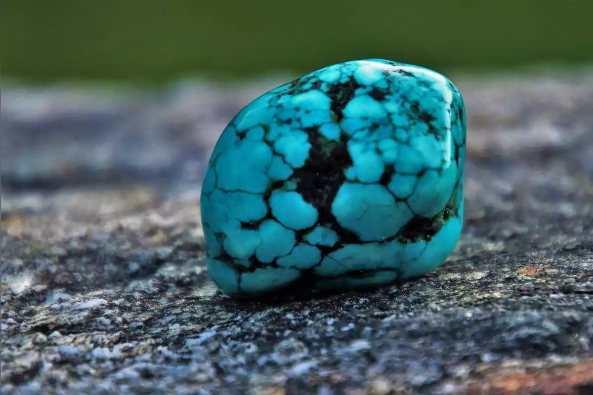 Una piedra turquesa de color azul claro sobre un fondo oscuro