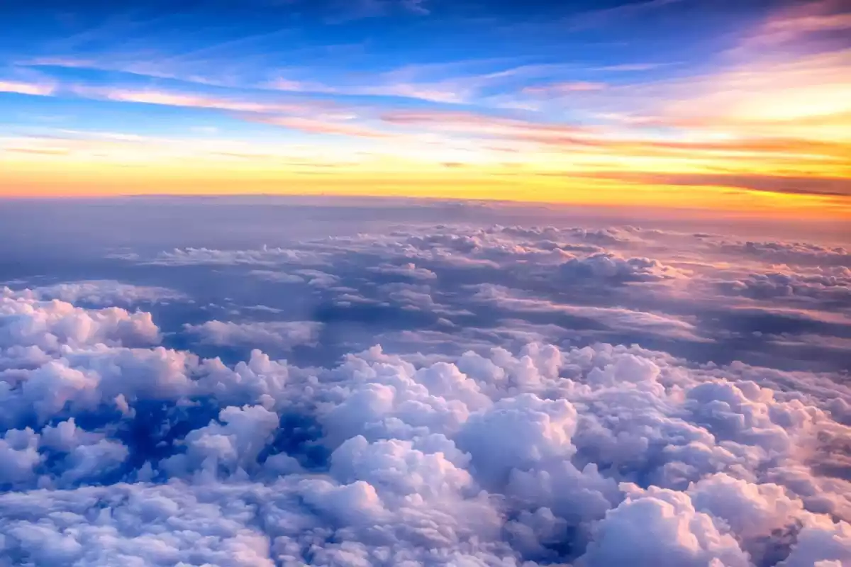 Imagen de una salida de sol entre nubes desde el aire