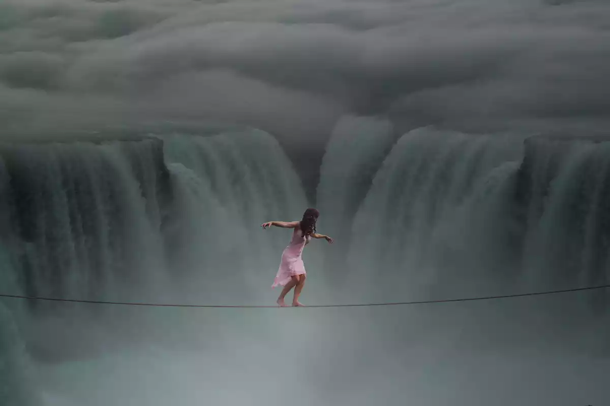 Una mujer cruzando una cascada sobre una cuerda en pijama