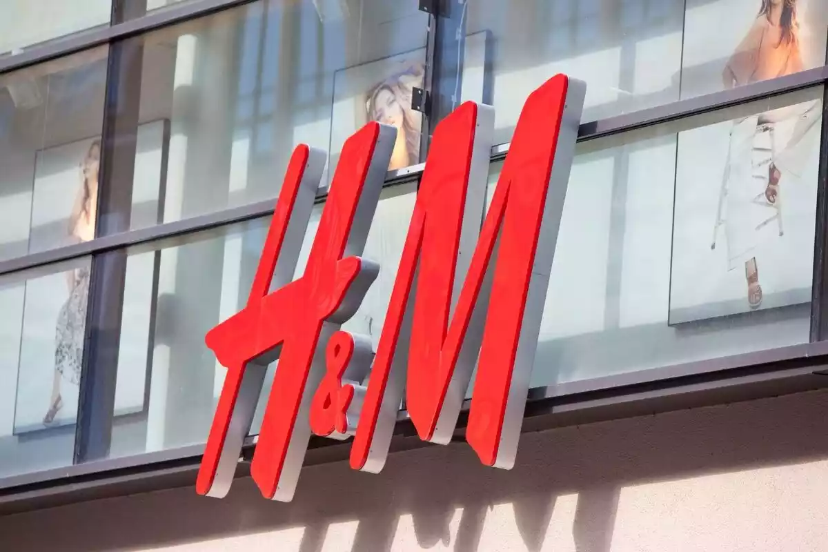 Logo de la cadena H&M en rojo con imágenes de modelos detrás