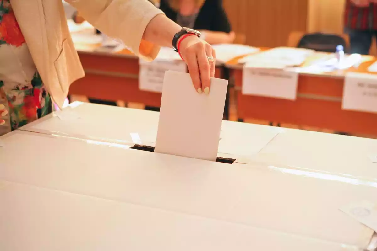 Chica introduciendo una carta de una votación en una urna