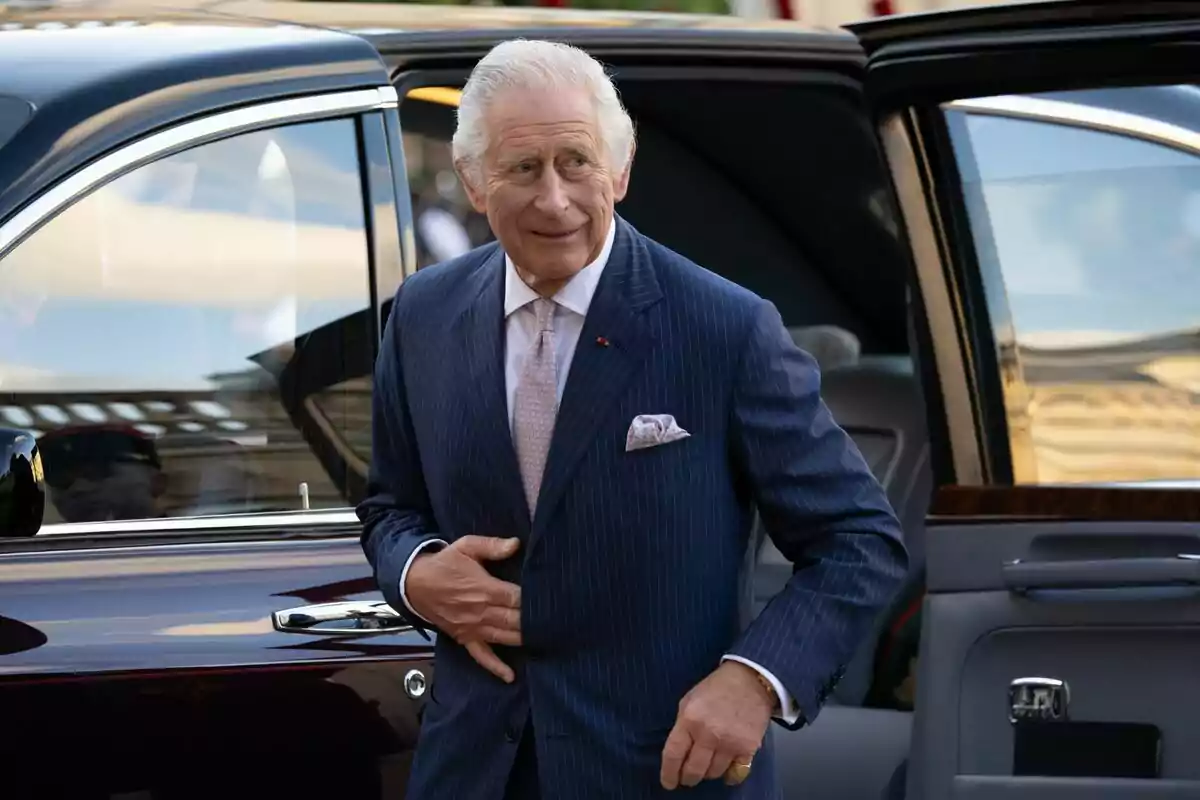 Carlos III in a blue striped suit gets out of an elegant car. Carlos III in a blue striped suit gets out of an elegant car.