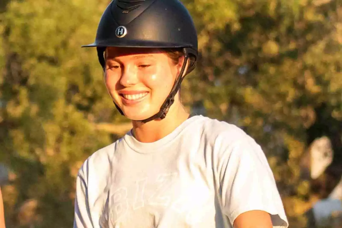 Cristina Iglesias sonriente con casco de equitación en un entorno al aire libre. Cristina Iglesias sonriente con casco de equitación en un entorno al aire libre.