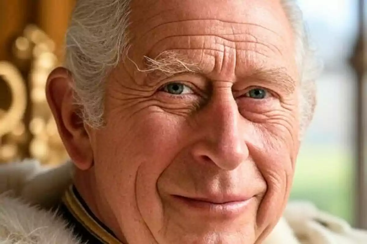 Close-up of King Charles III with a smiling expression and a blurred golden background.