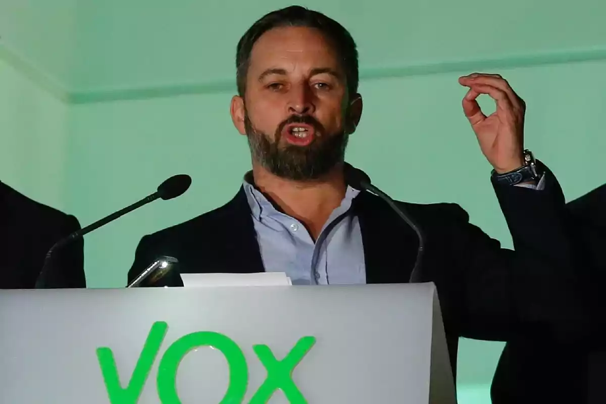 Un hombre hablando en un podio con el logo de un partido político.