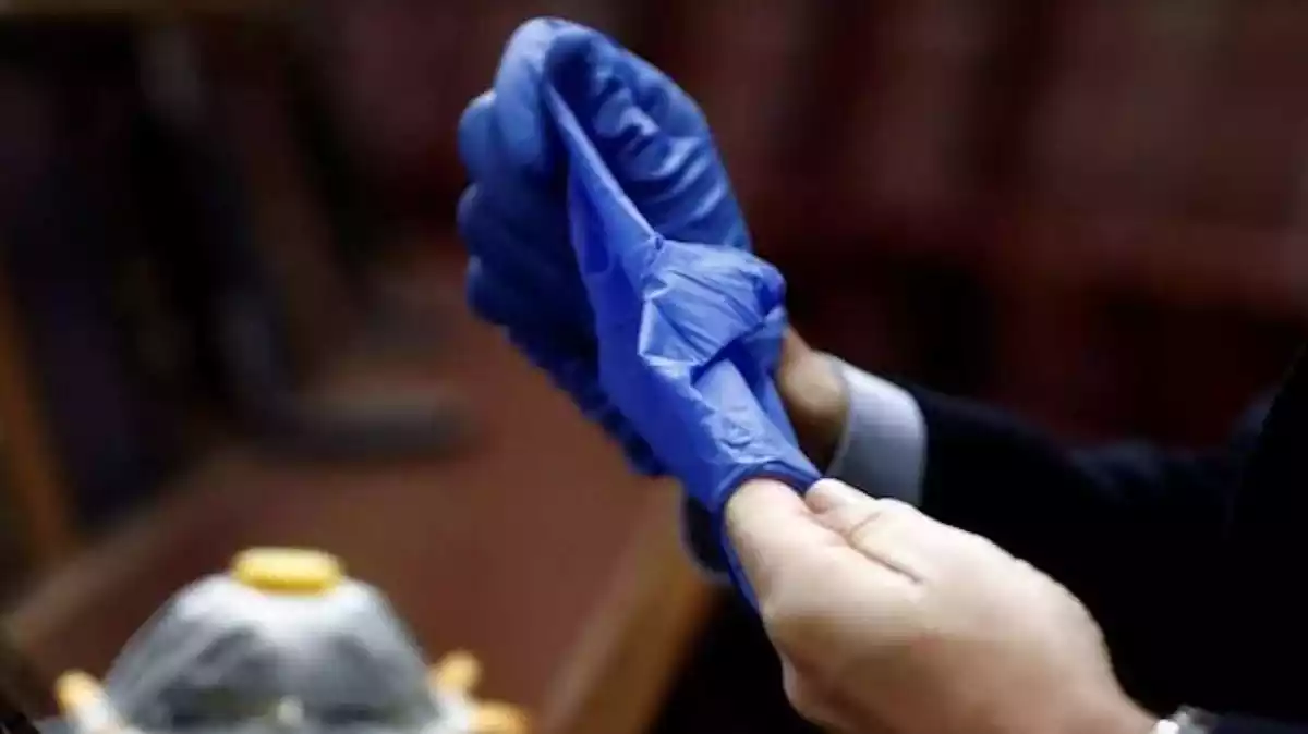 Persona quitándose los guantes de forma correcta para evitar contagio de Covid-19