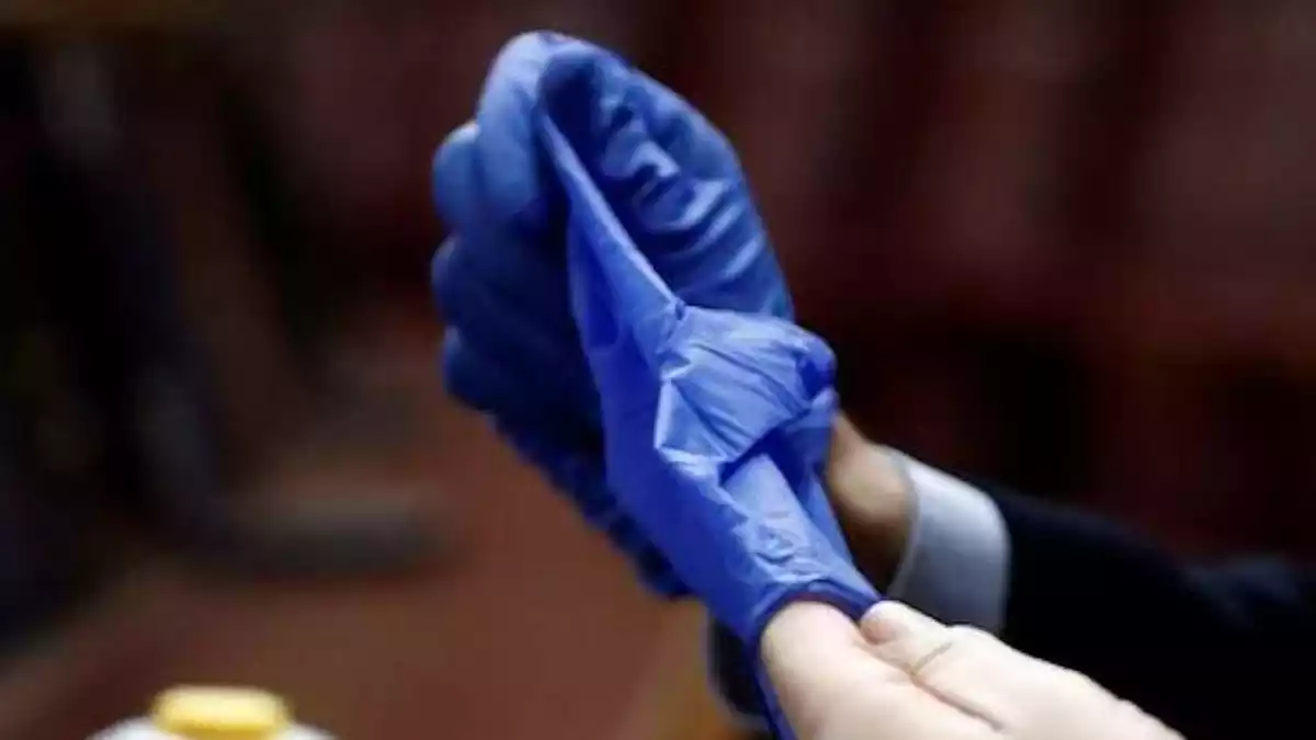 Persona quitándose los guantes de forma correcta para evitar contagio de Covid-19