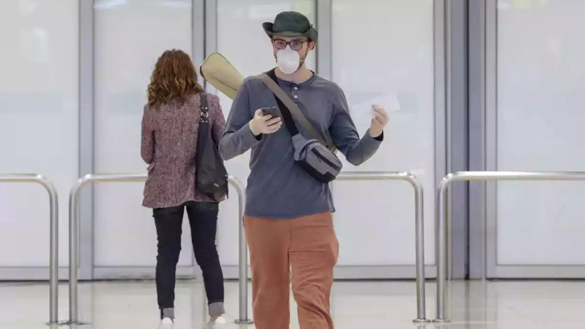 Una persona con mascarilla y guantes en un aeropuerto.